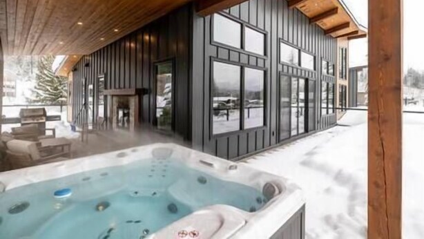 A modern building with large windows and a hot tub area. - Luxury 4 BDR Home / Hot tub / Amazing Fireplace! (Fernie)
