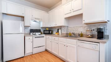 A modern kitchen with white cabinetry, a stainless steel refrigerator, a microwave, a stove, and a dishwasher.