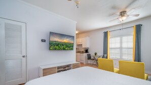 A bedroom with a bed, a TV mounted on the wall, a desk, and a chair. - Sunny Daze · Sunny Daze- Chic condo close to NASCAR (Concord)