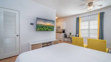 A bedroom with a bed, a TV mounted on the wall, a desk, and a chair.