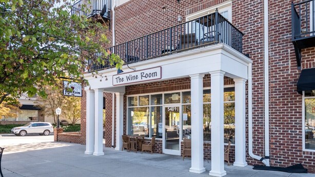 A brick building with a balcony and a sign reading "The Wine Room." - Sunny Daze · Sunny Daze- Chic condo close to NASCAR (Concord)