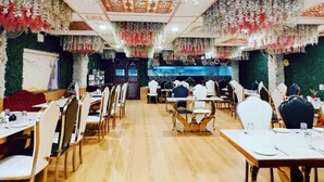 Un restaurant doté de nombreuses tables et chaises, décoré de compositions florales suspendues.