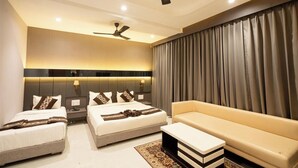 Une chambre d’hôtel moderne avec deux lits, un canapé, un ventilateur de plafond et une grande fenêtre avec des rideaux.
