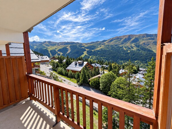 A balcony with a view of a mountainous landscape and a village below.