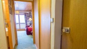Um corredor com um banco de madeira, uma porta e vista para um quarto com varanda.