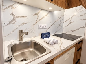 A modern kitchen with a marble backsplash, stainless steel sink, and a Bosch dishwasher.