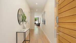A hallway with a wooden door, a mirror, a small table with a vase, and a chair. - Bondi Coastal Charm ISYD (Bondi Beach)