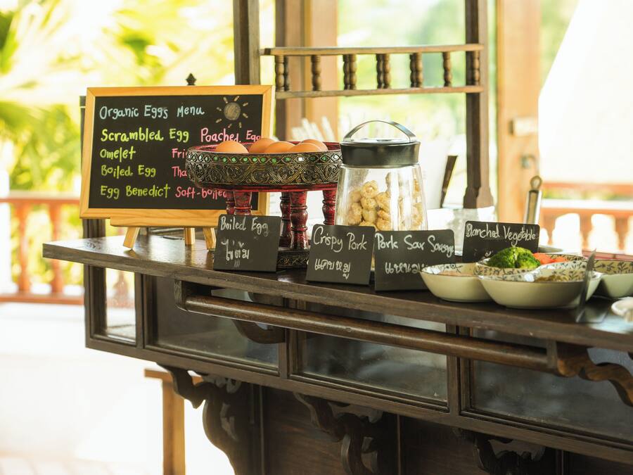 A breakfast buffet with various egg dishes and side items like crispy pork and baked vegetable.