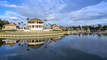 A large, circular building with a dome roof, surrounded by a body of water and palm trees.