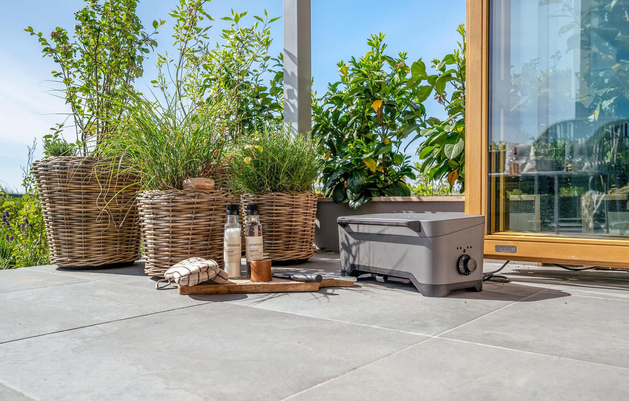 A patio area with wicker baskets, a portable heater, and potted plants.