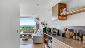 A modern kitchen with built-in appliances, a wooden upper shelf, and a view to the outdoors. - Gorgeous apartment in Kerteminde (Kerteminde)