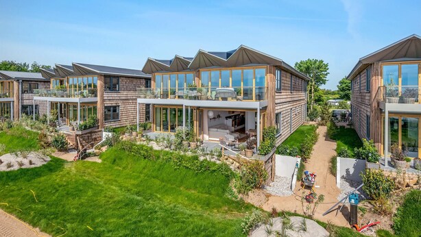A modern residential complex with multiple two-story houses featuring large glass windows, outdoor seating areas, and a well-maintained garden. - Gorgeous apartment in Kerteminde (Kerteminde)
