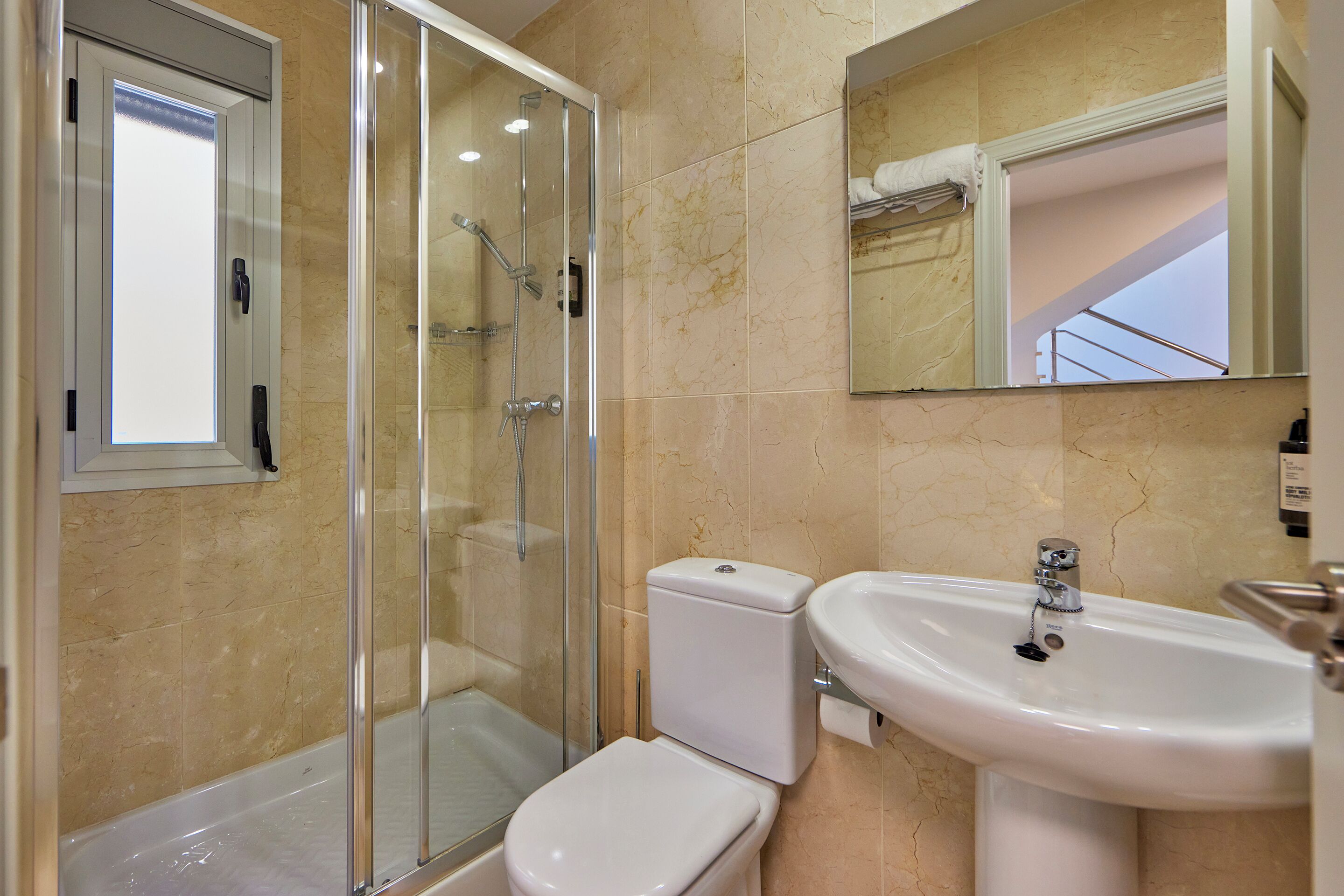 Un baño con ducha de vidrio, inodoro blanco y lavamanos.