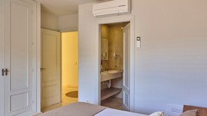 Een hotelkamer met een bed, een badkamer met een wastafel en spiegel, en een airconditioning.