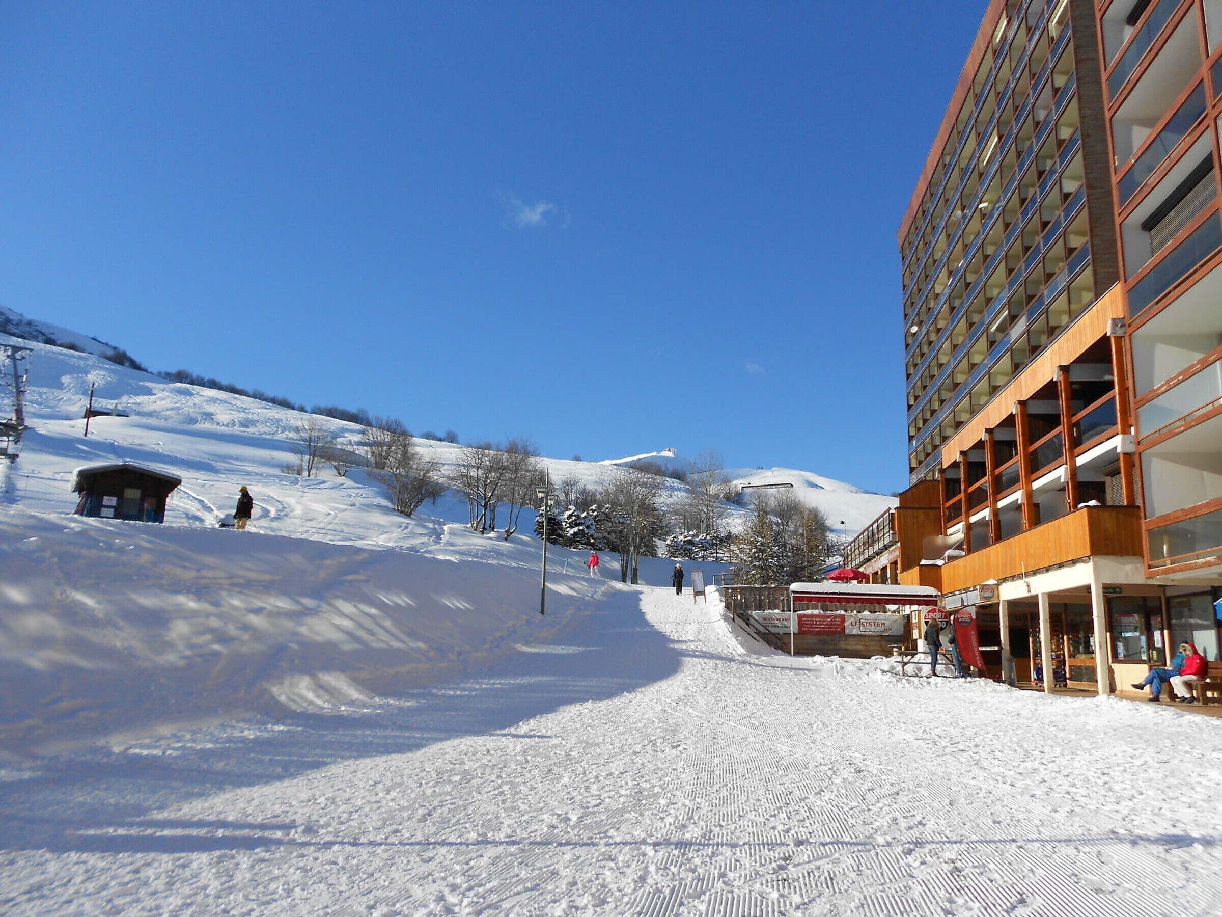 Ein mit Schnee bedeckter Skipisten mit einem Gebäude auf der rechten Seite.