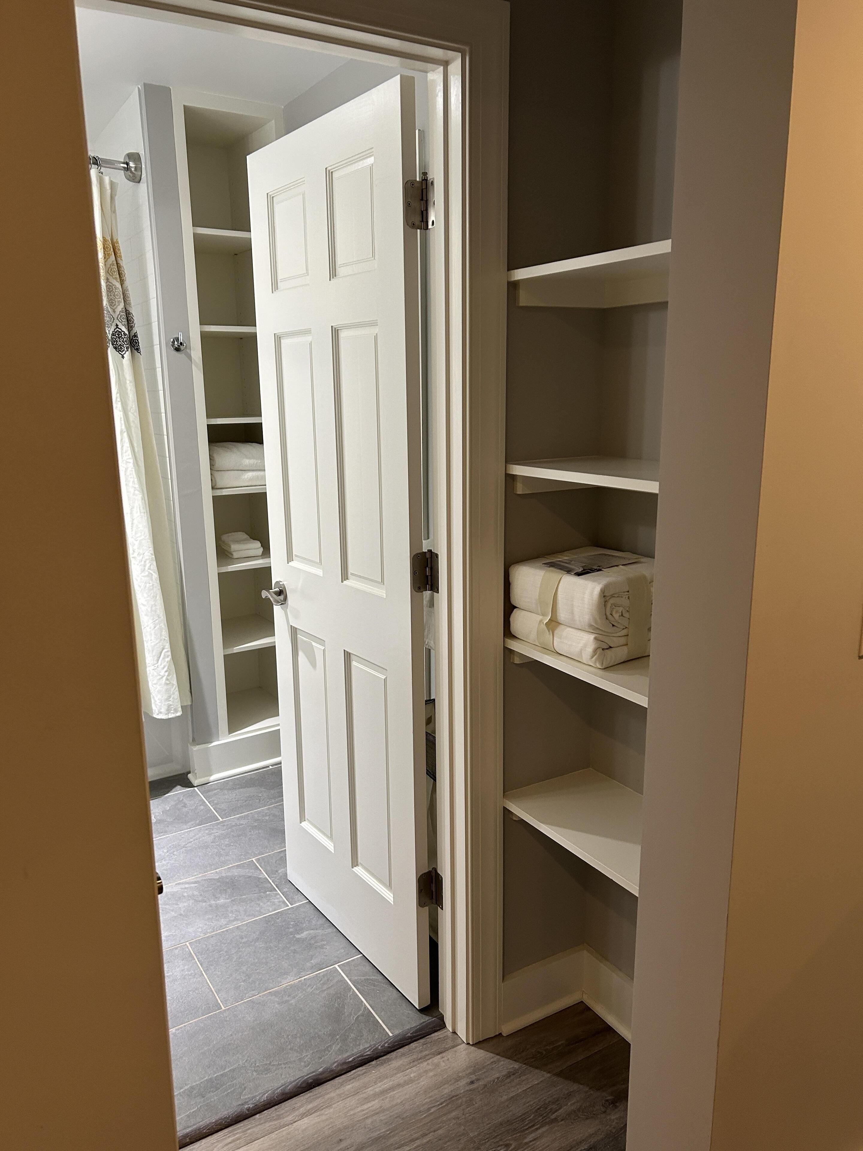 A walk-in closet with open doors, revealing shelves and hanging space.