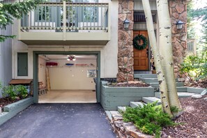Une maison à deux étages avec un porche à l’avant, une façade en pierre et une porte en bois ornée d’une guirlande.