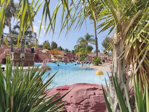 A pool area with water slides, palm trees, and a bridge. - Camping Tikayan Les Palmiers (Hyères)