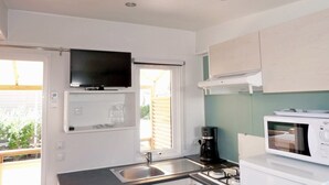 A compact kitchen with a built-in TV, a coffee maker, a microwave, and a sink. - Camping Tikayan Les Palmiers (Hyères)
