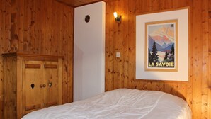 Ein Schlafzimmer mit Holzwänden, einem Bett, einem Kleiderschrank und einem Bild an der Wand.
