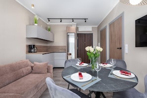 A modern dining area with a round table, chairs, and a vase of flowers.