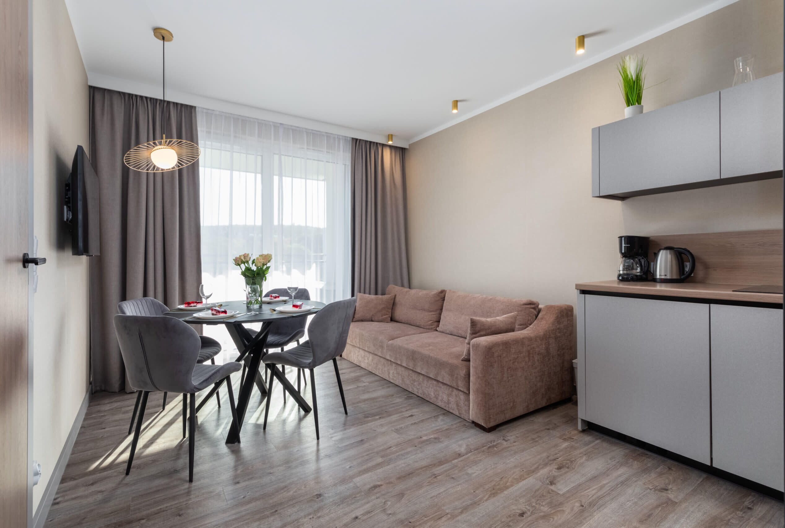 A bright living room with a modern sofa, dining table, and soft lighting, offering a comfortable space to relax.
