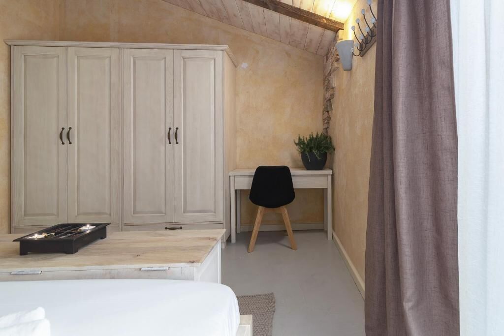 A bedroom with a bed, a desk, and a wardrobe.