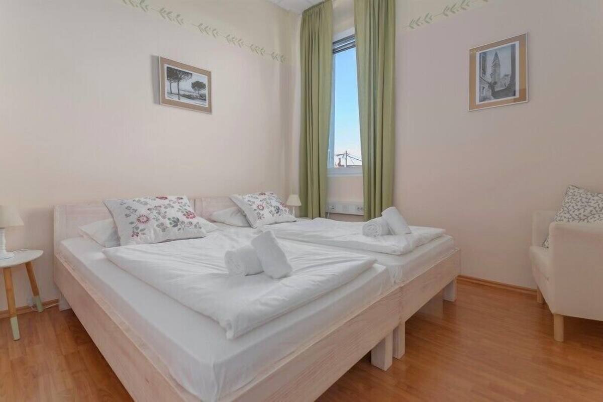 A double bed with floral pillows, a small bedside table, and a chair.