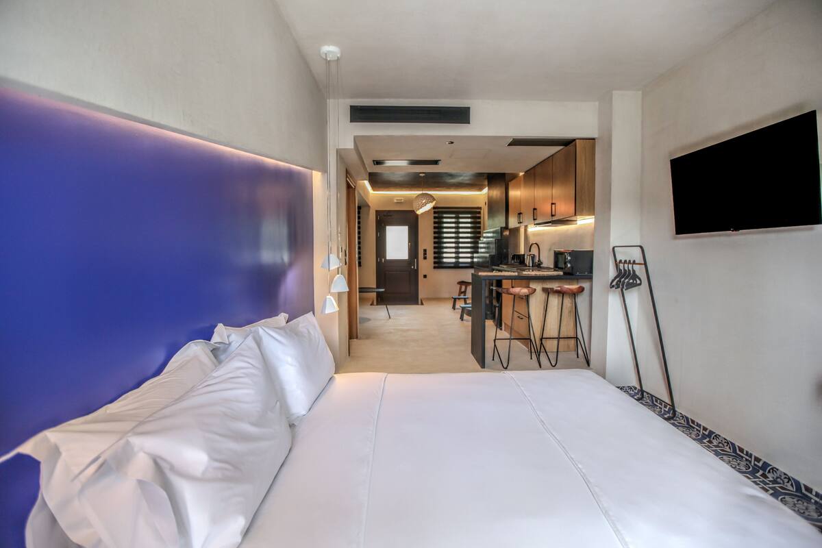 A hotel room with a large bed, a desk, and a TV mounted on the wall.