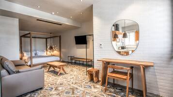 Una habitación de hotel moderna con cama, sofá, mesa de madera y un espejo grande.