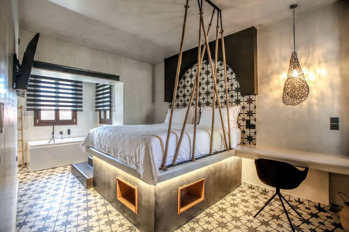 A modern bedroom with a unique bed design, a large mirror, and a hanging light fixture.