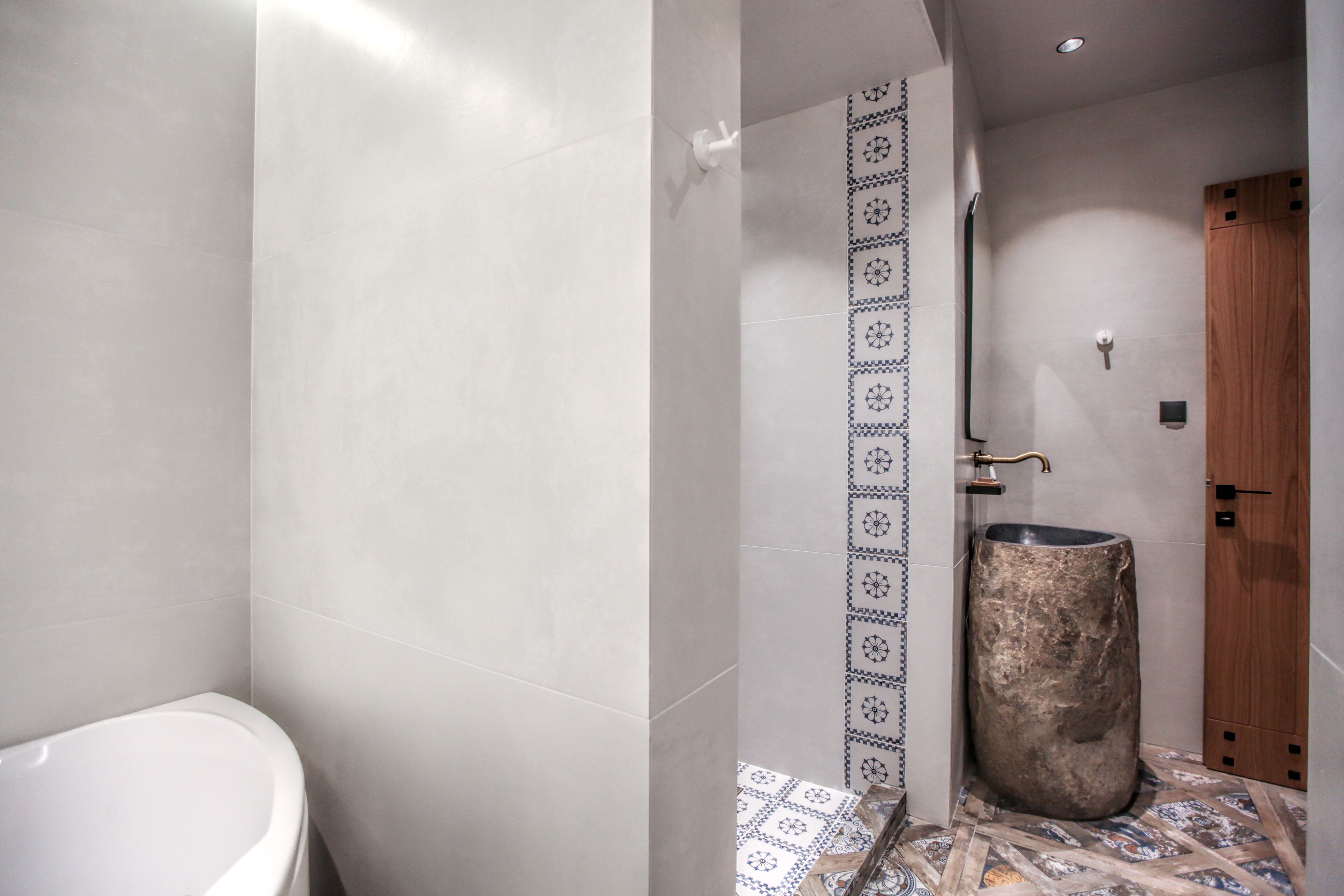 A modern bathroom with a bathtub, a shower with a large stone basin, and patterned tiles.