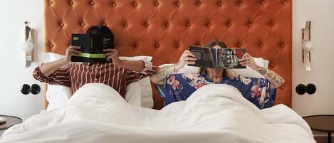 Dos personas acostadas en la cama leyendo libros.