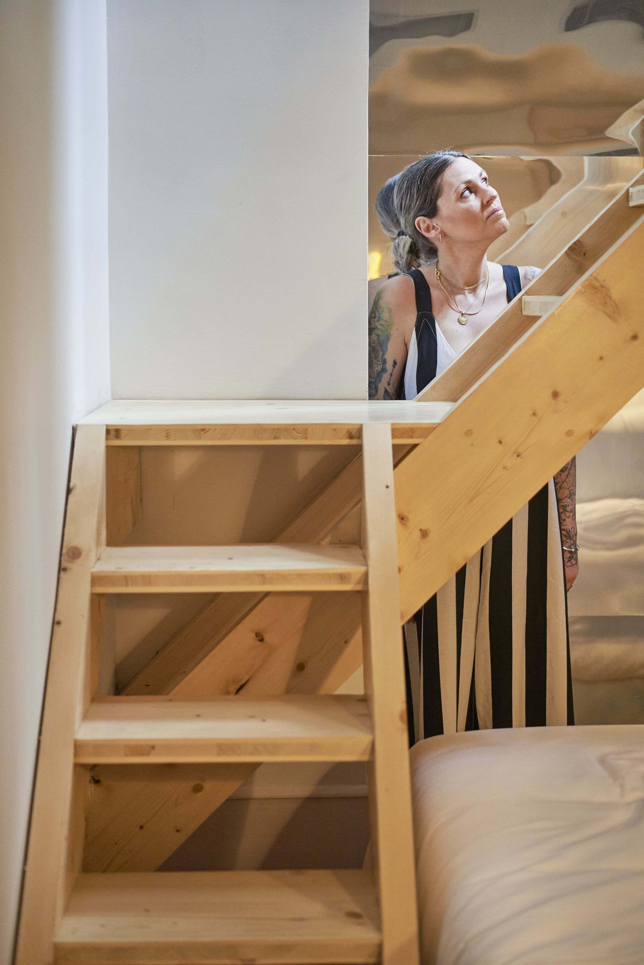 A wooden staircase with a person standing at the top.