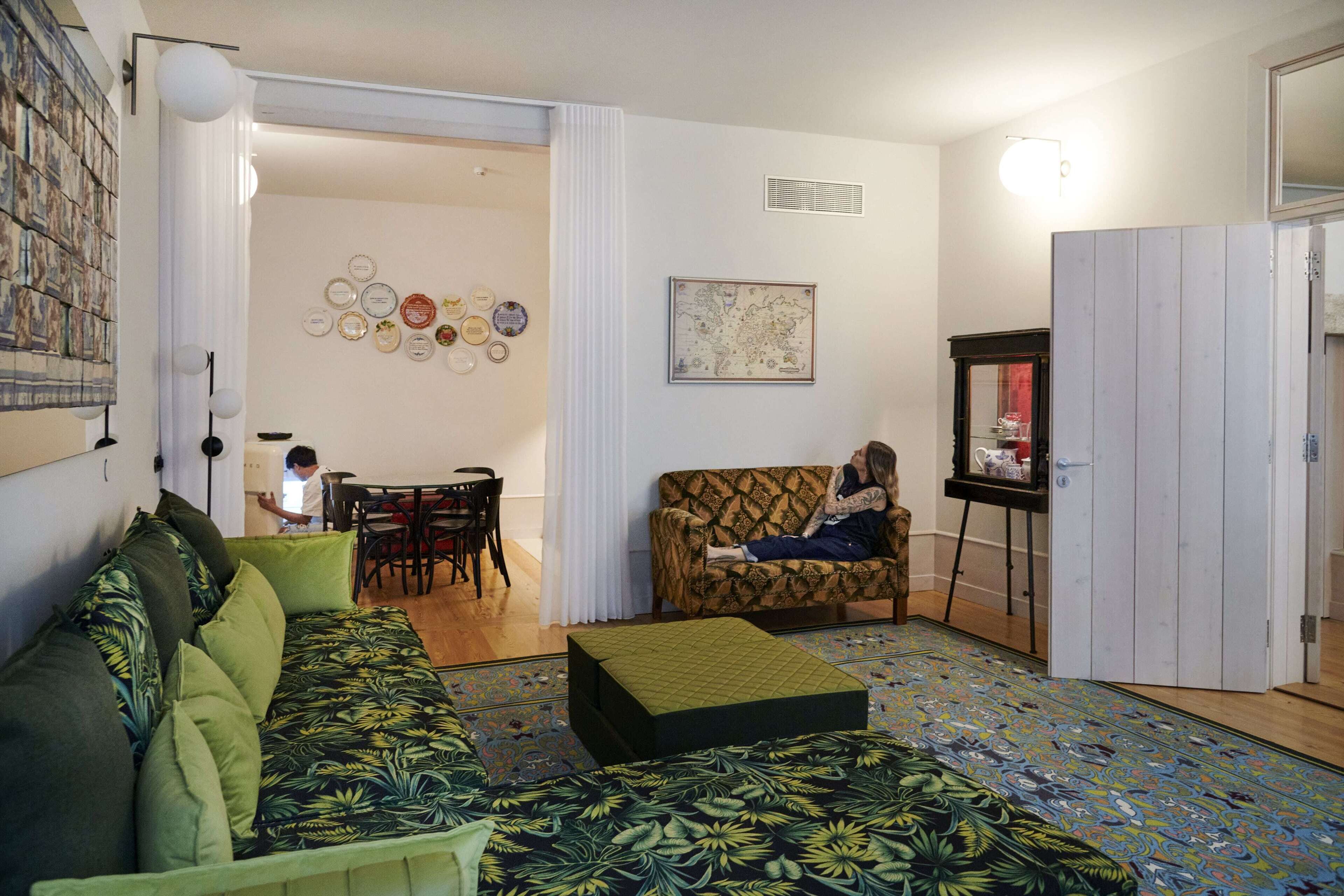 Un salon comprenant un canapé, un fauteuil à motifs, une table basse, une table à manger avec des chaises et un buffet.