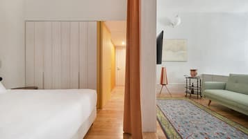 A bedroom with a bed, a wardrobe, a television, a sofa, and a patterned rug.