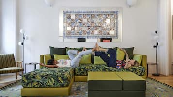 Et værelse med en stor sofa, et mønstret tæppe og et kunstværk på væggen.