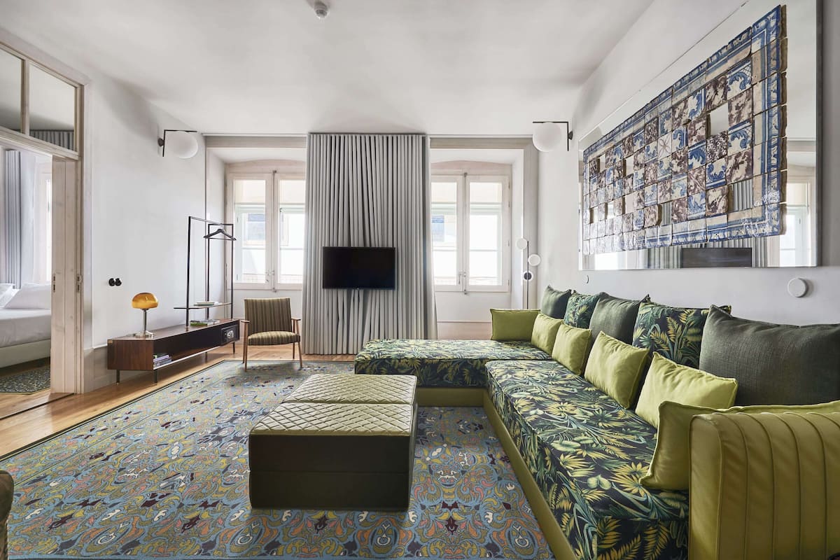 Una sala de estar moderna con un sofá seccional, un televisor de pantalla plana, un tapete estampado y una pared de azulejos decorativos de gran tamaño.