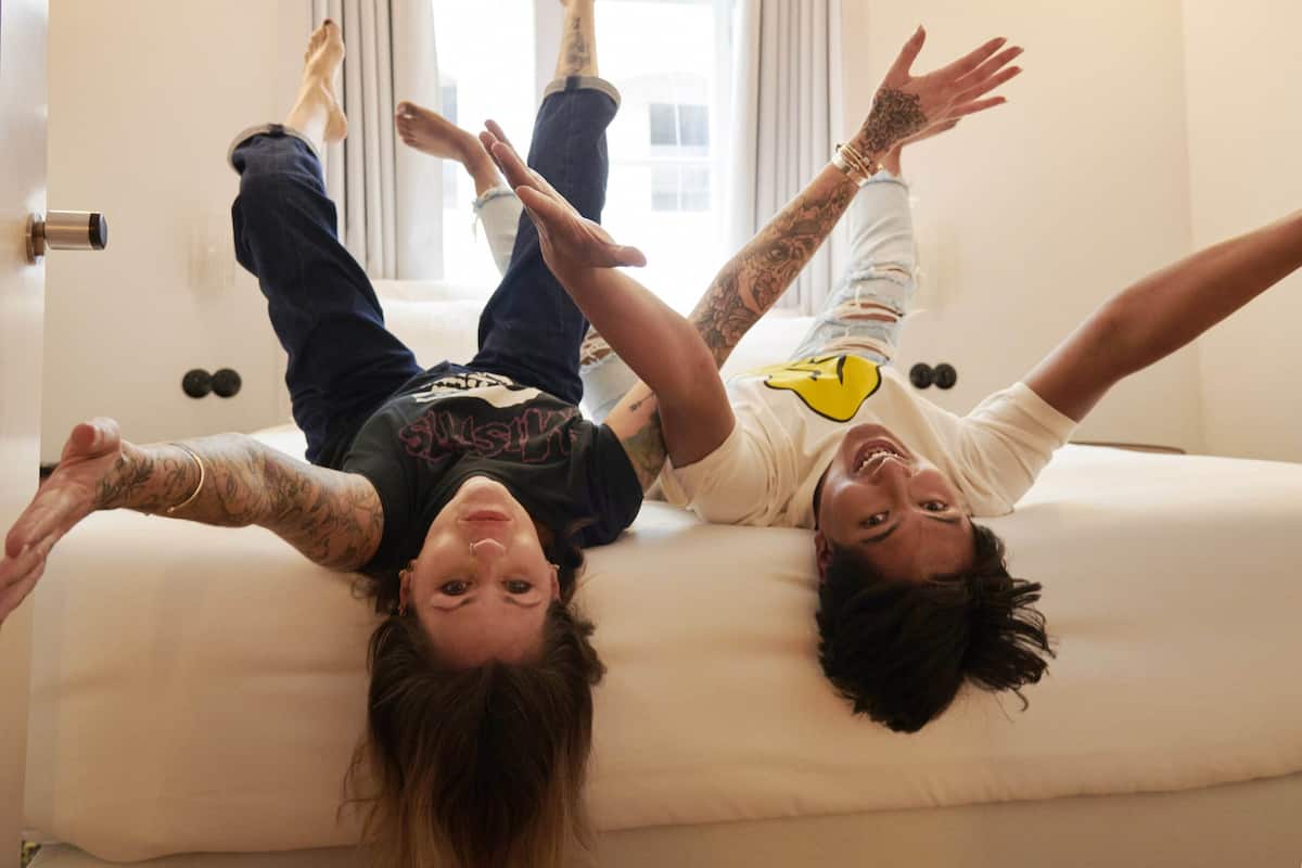 Dos personas acostadas en una cama con una ventana al fondo.