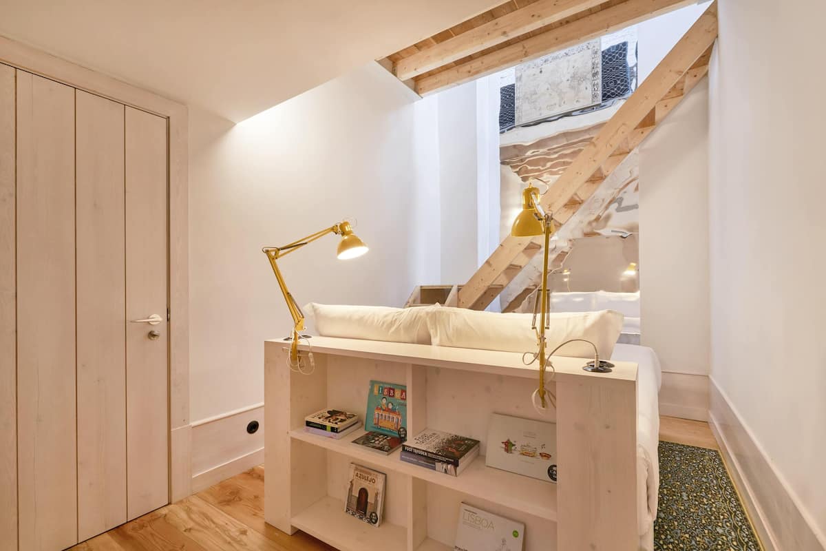 Un dormitorio con cama altillo, estanterías de madera con libros y una escalera.
