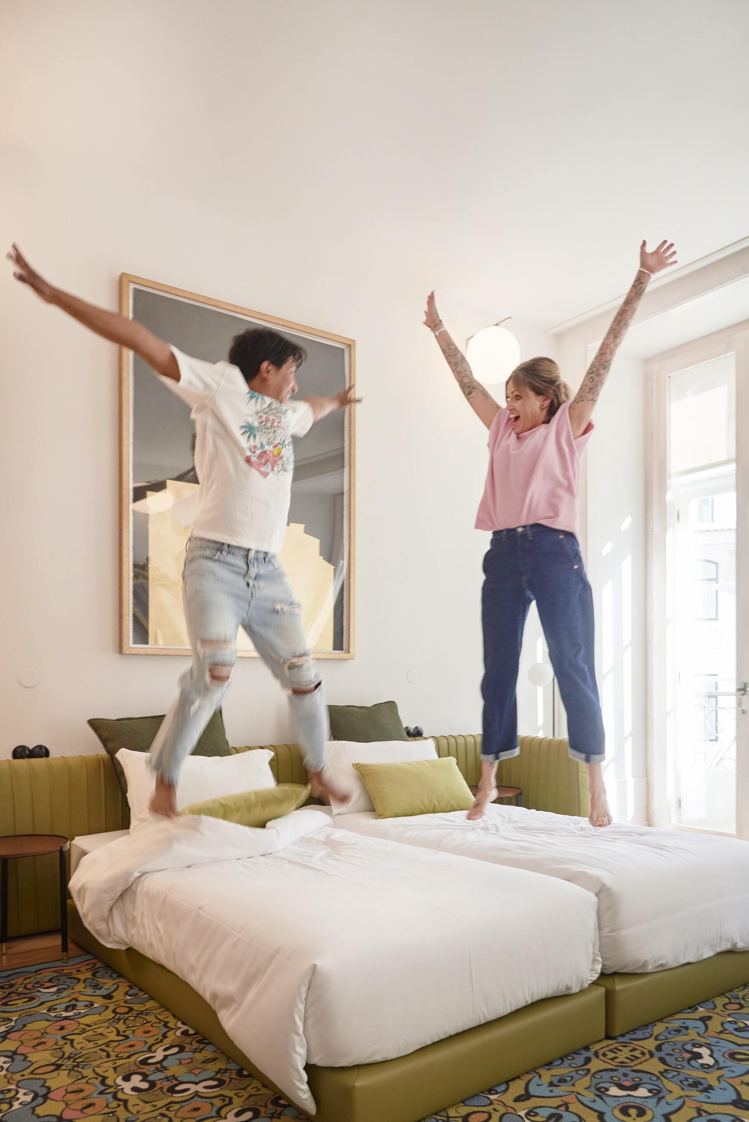Une pièce avec un lit, un canapé vert et un grand tableau accroché au mur.