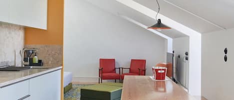 Una cocina moderna con armarios blancos, una mesa de comedor de madera y sillas rojas.