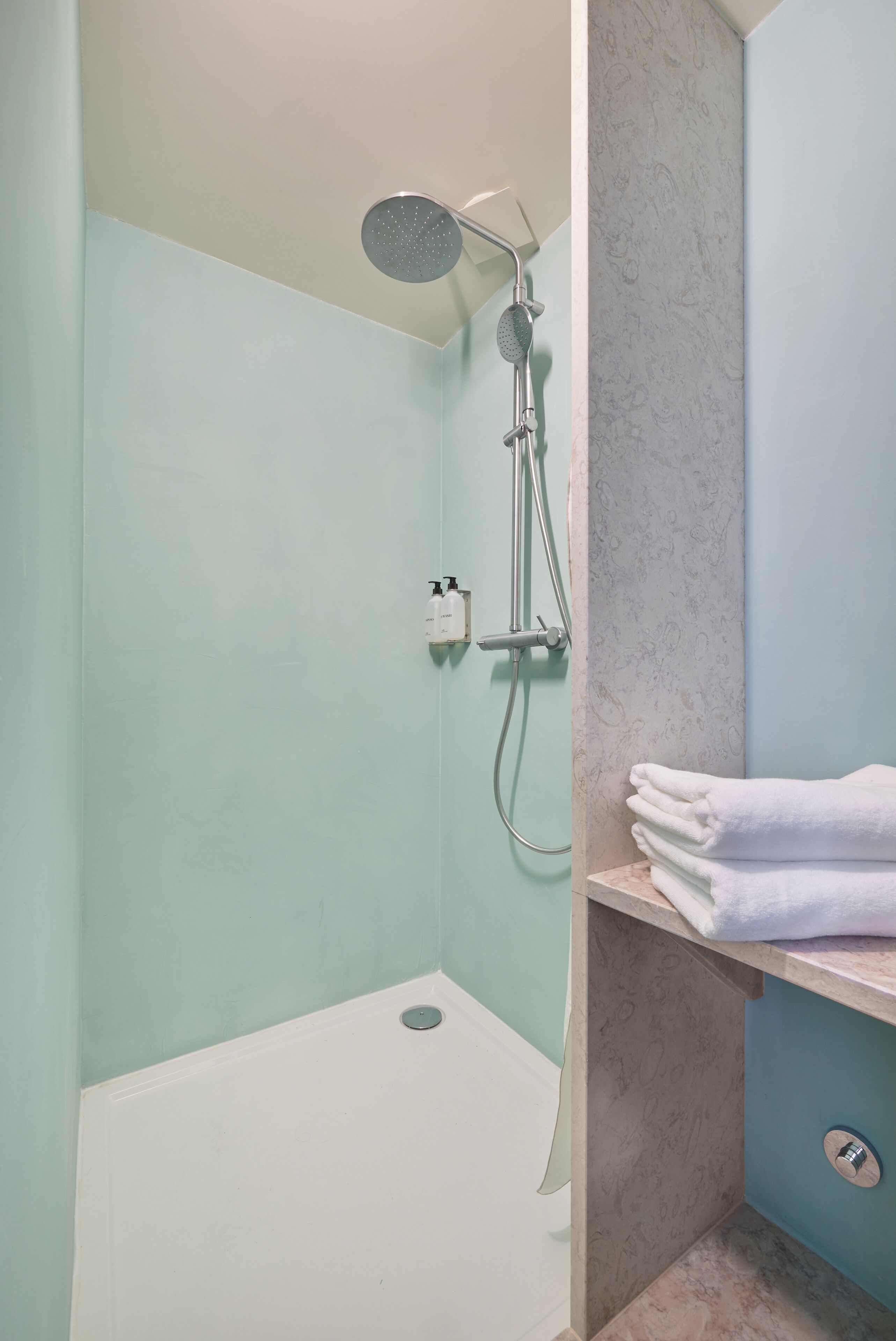 A bathroom with a shower, a sink, and a towel rack.