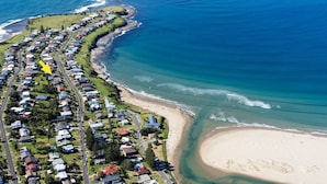 An aerial view of a coastal residential area with houses along the beachfront, a sandy beach, and a clear blue ocean. - Banksia by the Sea, Gerroa (Gerroa)
