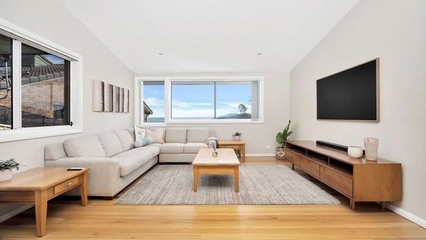 A modern living room with a sectional sofa, a coffee table, a TV, and a large window with a view of the sea. - Banksia by the Sea, Gerroa (Gerroa)