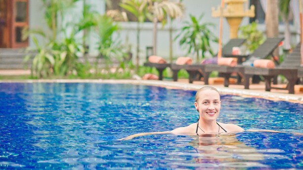 Una piscina con agua cristalina, rodeada de tumbonas y palmeras.