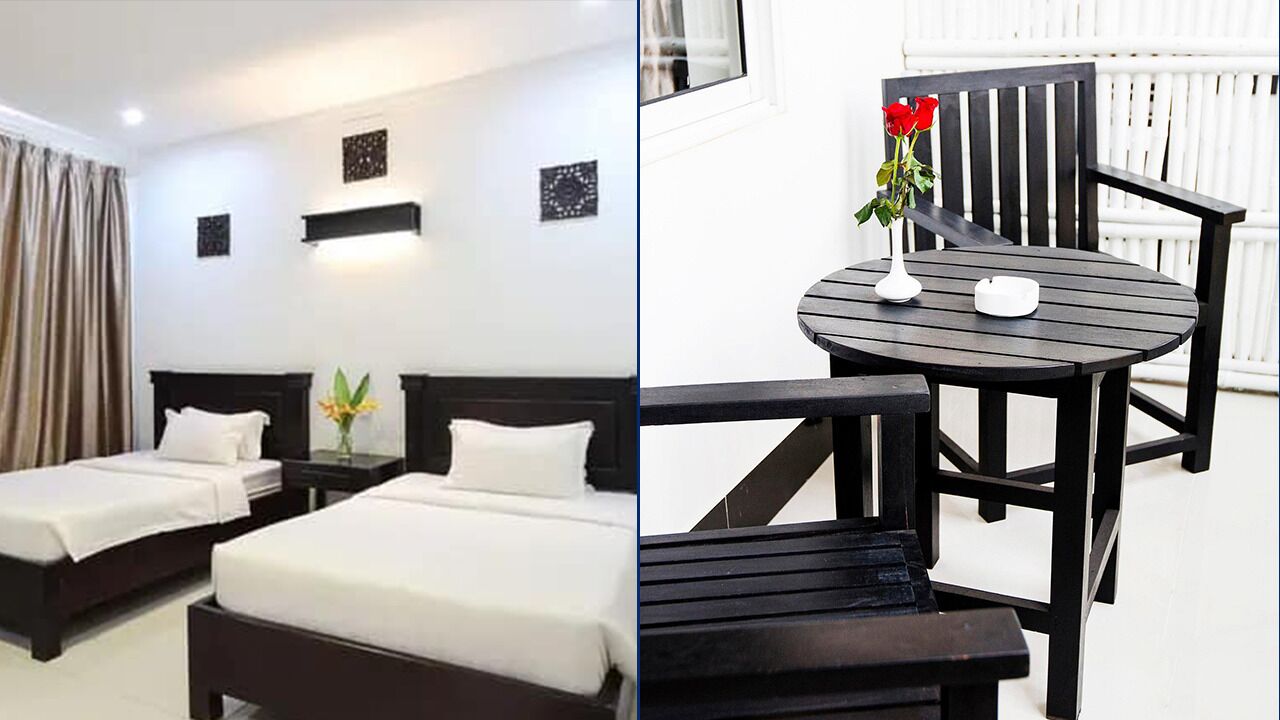 A hotel room with two beds, a small table with a vase of flowers, and a chair.