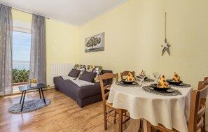Relax in this inviting living room with a sofa, dining table, and large window offering a view of the outdoors.