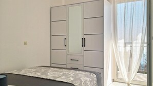Une chambre avec un lit, une armoire et un balcon offrant une vue.