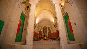 An interior with arched ceilings, green doors, and a central table with chairs.